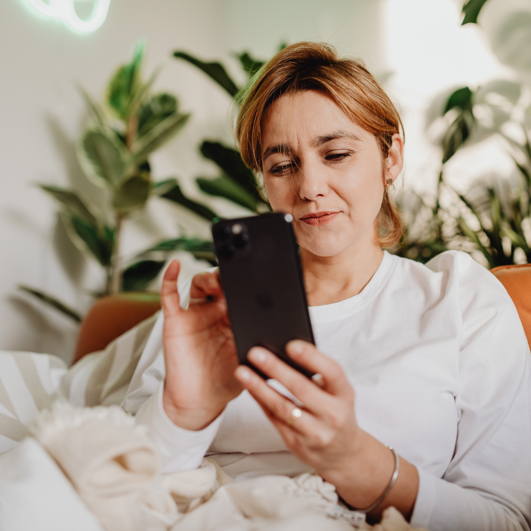 Kvinna använder smartphone i soffan hemma